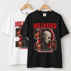 Pode incluir: Uma t-shirt preta e uma branca de manga curta com uma impressão gráfica de Hellraiser. O design inclui o texto HELLRAISER, PAIN PLEASURE ETERNITY, A CLIVE BARKER FILM e WE HAVE SUCH SIGHTS TO SHOW YOU, junto com imagens de Pinhead e Kirsty Cotton.