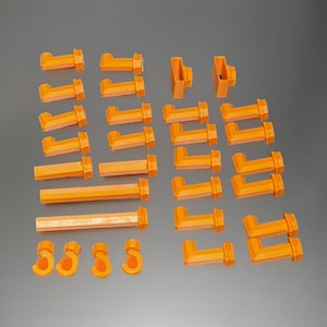 Könnte beinhalten: Ein Satz mit 30 orangefarbenen Kunststoffverbindern zum Bau eines Modells oder einer Struktur. Die Verbinder umfassen gerade, abgewinkelte und gebogene Teile.