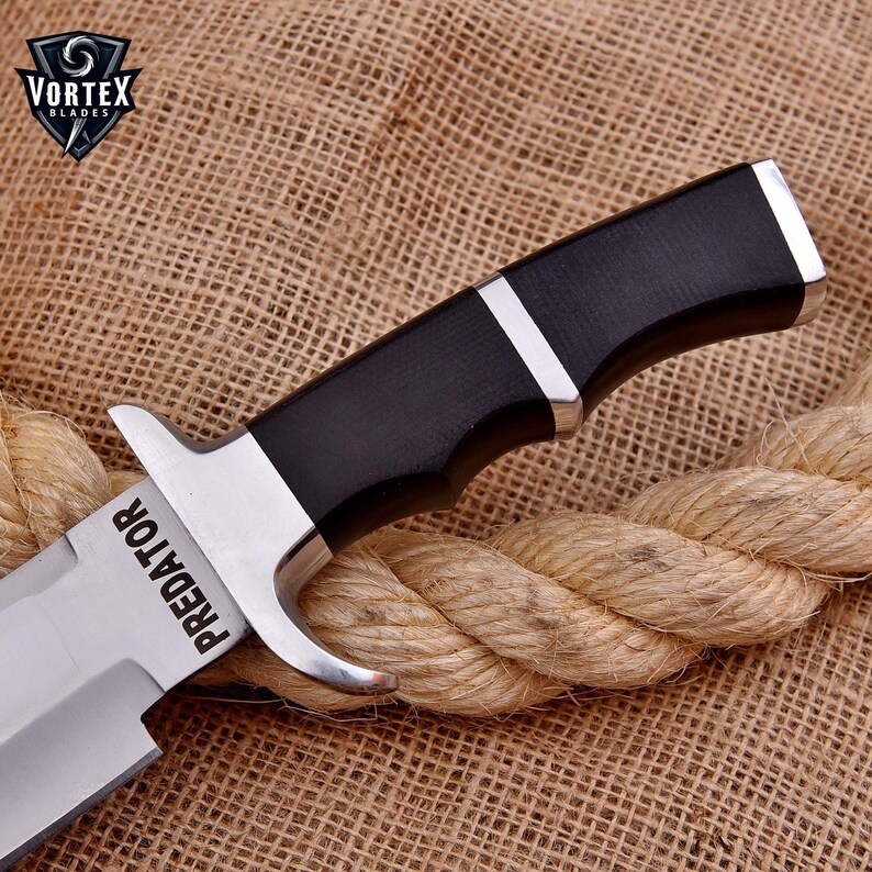 May include: A silver and black hunting knife with a black handle and the word "PREDATOR" engraved on the blade.