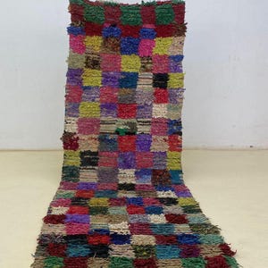 Peut inclure: Un tapis rectangulaire coloré avec un motif patchwork. Le tapis présente une variété de couleurs, notamment le rouge, le vert, le bleu, le jaune et le violet. Le tapis est fait d'un matériau texturé et a un bord effiloché. Idéal pour un salon ou une chambre.