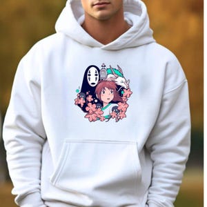 May include: White hooded sweatshirt with a vibrant graphic of anime characters. The design includes a girl, a dragon, and a faceless spirit, framed by pink flowers. The graphic is centrally placed on the front.