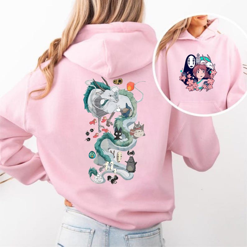 May include: Pale pink hoodie with a vibrant illustration of a dragon and other characters from an animated film. The back of the hoodie features a large dragon design, and the front pocket area has a smaller graphic of characters and flowers.