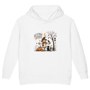 Puede incluir: Una sudadera con capucha blanca que presenta una ilustración gráfica de un espantapájaros con sombrero, un gato negro, calabazas, una luna creciente y un farol. El texto "AUTUMN SPOOKS" está impreso en color marrón oscuro sobre la figura.
