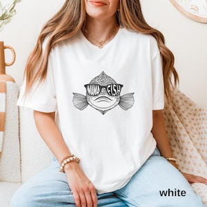 May include: White t-shirt with a black and white illustration of a fish wearing sunglasses. The fish's eye is a circle with the text "Mama Fish" inside.