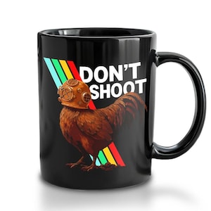 Könnte beinhalten: Schwarze Keramik-Tasse mit einem braunen Hahn, der einen Vintage-Tauchhelm trägt. Die Tasse hat den weißen Text "DON'T SHOOT" und ein farbenfrohes diagonales Streifendesign. Die Tasse hat einen schwarzen Griff.
