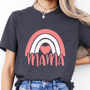 May include: Dark gray t-shirt featuring a pink and white rainbow design with a heart and the word "MAMA" in pink. The shirt is made of a soft material and is suitable for casual wear.