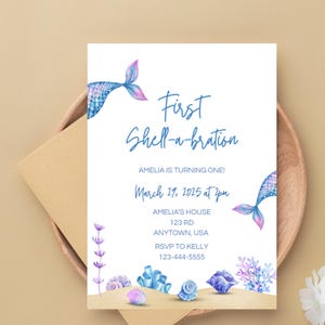 May include: A blue and purple mermaid tail with a white background. The text "First Shell-a-bration" is written in blue cursive. The text "Amelia is turning one!" is written in blue. The text "March 29, 2025 at 2pm" is written in blue. The text "Amelia's House 123 Rd Anytown, USA" is written in blue. The text "RSVP to Kelly 123-444-5555" is written in blue. The image is a printable invitation for a first birthday party.