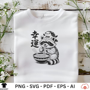 May include: White t-shirt featuring a black and white illustration of a raccoon eating ramen from a bowl. A turtle sits on the raccoon's head. The Japanese characters for "good luck" are on the left side of the design. The shirt has a crew neck.