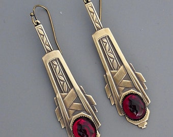 May include: A pair of gold-tone dangle earrings with geometric designs and red glass stones.