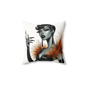 Puede incluir: Cojín cuadrado con una ilustración en escala de grises de una mujer con maquillaje dramático y peinado flapper. La mujer está adornada con plumas naranjas y negras y largos guantes negros. El cojín tiene un fondo blanco.