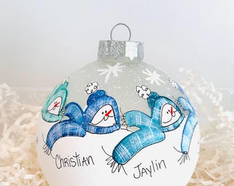 May include: A hand-painted Christmas ornament featuring three snowman figures wearing blue plaid scarves and hats. The names "Christian" and "Jaylin" are written on the ornament, along with the year "2025". The ornament has a silver metal cap and is decorated with snowflakes.