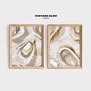 May include: Two framed prints with a pattern of gold and white oyster shells on a beige background. The text "Vintage Glow Prints" is at the top of the image.