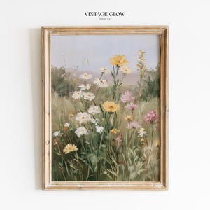 以下が含まれることがあります： 黄色、白、ピンクの色合いの野草が描かれた、額入りの花のプリント。このアートワークは、柔らかく絵画的なスタイルで、ヴィンテージな美学を持っています。フレームは、明るく、使い古されたゴールド色です。「VINTAGE GLOW PRINTS」の文字が上部にあります。