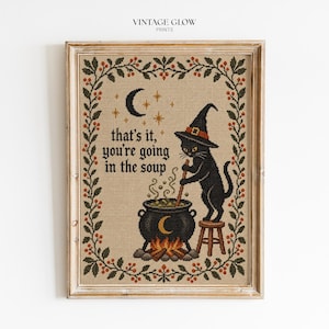 Puede incluir: Una pieza de arte en punto de cruz enmarcada con un gato negro con sombrero de bruja, de pie sobre un taburete y revolviendo un caldero sobre un fuego. El texto dice, that's it, you're going in the soup. Borde de hojas verdes y bayas rojas.