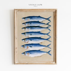 May include: A framed print depicting seven blue fish arranged vertically on a beige background. The fish have white highlights and are painted in a realistic style. The frame is light wood, and the text "VINTAGE GLOW PRINTS" is at the top.