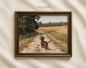 May include: A framed landscape painting featuring a brown dachshund walking away on a dirt path through a golden field, with trees on the left and a distant horizon under a pale sky. The text VINTAGE GLOW PRINTS is centred above the frame.