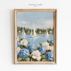 Puede incluir: Una lámina enmarcada titulada VINTAGE GLOW PRINTS que muestra una pintura de tres veleros blancos en un tranquilo cuerpo de agua azul. El primer plano está lleno de racimos de hortensias azules y blancas frente a una línea de árboles.