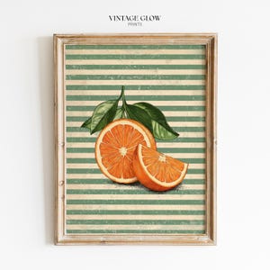 May include: A framed wall art print featuring a whole orange slice and a wedge with green leaves, set against a background of horizontal sage green and off-white stripes with a distressed, weathered texture throughout the entire composition.
