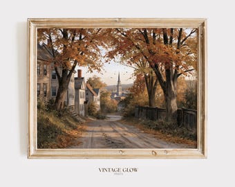 May include: A framed landscape art print depicting a dirt road leading through a town during autumn. The scene features houses, large trees with orange and yellow foliage, and a church steeple in the distance. The text VINTAGE GLOW PRINTS is visible.