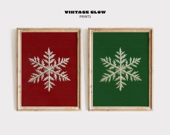 Könnte beinhalten: Zwei gerahmte Drucke mit Schneeflocken-Designs. Einer hat einen roten Hintergrund, der andere ist grün. Die Schneeflocken sind weiß und detailliert. Der Text "VINTAGE GLOW PRINTS" steht oben.