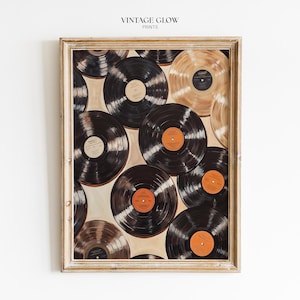 Könnte beinhalten: Ein gerahmter Kunstdruck mit dem Titel VINTAGE GLOW PRINTS, der eine Collage aus mehreren Schallplatten in Schwarz- und Goldtönen zeigt. Die Platten sind überlappend angeordnet und weisen deutlich sichtbare Mittellabels in Orange- und Beigetönen auf.