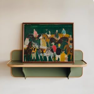 May include: An abstract painting of a horse race, framed in dark wood, hangs above a green and tan shelf. The artwork features riders and horses in various colors against a green background. The shelf has a curved design.