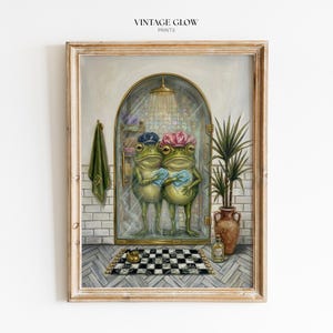Peut inclure: Impression artistique encadrée représentant deux grenouilles anthropomorphes dans une douche, coiffées de bonnets de douche et tenant des gants de toilette. L'œuvre comprend un tapis en damier, une serviette verte et une plante en pot. Le texte "VINTAGE GLOW PRINTS" est en haut.