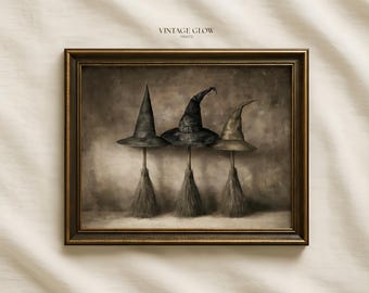 May include: A framed wall art print titled VINTAGE GLOW PRINTS featuring three pointed hats resting on top of broomsticks. The hats are rendered in shades of black, gray, and muted brown against a textured, neutral-toned background.