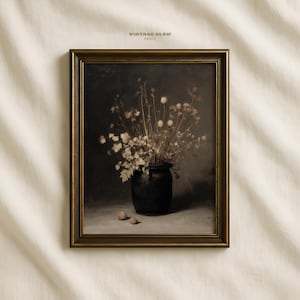 May include: A framed vintage print featuring a still life of dried flowers in a dark vase. The artwork has a muted color palette with a gold-toned frame. The text "VINTAGE GLOW PRINTS" is at the top.