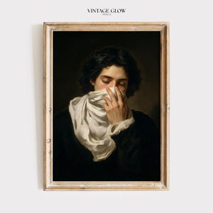 May include: A framed art print titled VINTAGE GLOW PRINTS featuring a portrait of a person with dark hair wearing a black garment and a white scarf covering the lower face. The person has eyes closed and one hand raised to hold the white fabric.