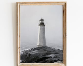 May include: A framed wall art print featuring a black and white illustration of a lighthouse standing on dark, jagged rocks amidst a misty sea. The text VINTAGE GLOW PRINTS is centered at the top. The artwork is enclosed in a light wood frame.