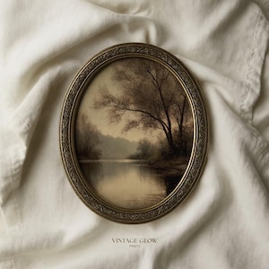 May include: An oval-shaped picture frame with an ornate, textured gold border containing a sepia-toned landscape print of a river and trees. Below the frame, the text VINTAGE GLOW PRINTS is printed in a simple, dark, sans-serif font.