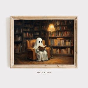 May include: A framed art print featuring a white ghost draped in a sheet sitting in a brown leather armchair reading a book. The scene is set in a dark library with tall wooden bookshelves filled with books and a lit floor lamp. Text reads VINTAGE GLOW PRINTS.