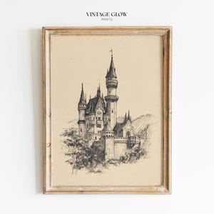 以下が含まれることがあります： 複数の塔と塔のある城の詳細なペンとインクの描画が特徴の、額装されたヴィンテージプリント。 アートワークはベージュの背景に設定され、明るい色の木製フレームに収められています。 上部には「VINTAGE GLOW PRINTS」というテキストがあります。