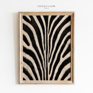 May include: A framed wall art print featuring a high-contrast black and white zebra stripe pattern. The rectangular wooden frame has a weathered, light brown finish. The text VINTAGE GLOW PRINTS is centered at the top of the image.