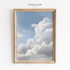 Könnte beinhalten: Ein gerahmter Druck mit einem bewölkten Himmel vor hellblauem Hintergrund. Die Wolken sind weiß und grau, mit einer weichen, malerischen Textur. Der Rahmen ist hell, naturfarben, mit dem Text "VINTAGE GLOW PRINTS" oben.