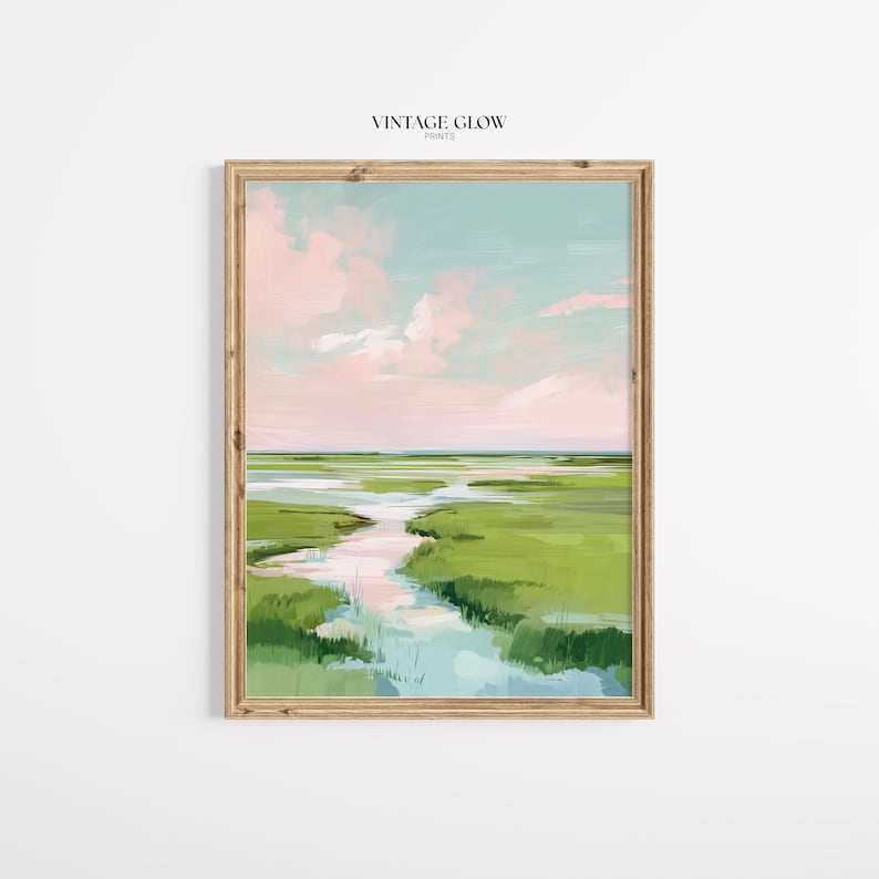 May include: A framed landscape art print depicting a marsh scene with a river. The artwork features green grass, a pink and blue sky, and a wooden frame. The text "VINTAGE GLOW PRINTS" is at the top of the print.