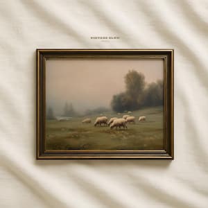 May include: A framed landscape print depicting sheep grazing in a field, with a vintage aesthetic. The artwork has a muted colour palette and a hazy atmosphere. The frame is a dark, ornate gold colour. The text "VINTAGE GLOW PRINTS" is visible.