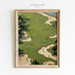 May include: A framed art print titled VINTAGE GLOW PRINTS featuring an aerial view of a golf course with green fairways, sand bunkers, and small figures of golfers in various colored shirts scattered across the landscape in a painterly style.