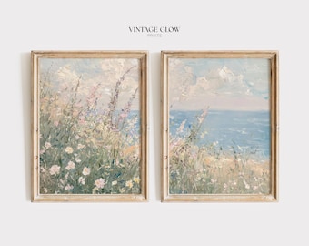 Peut inclure: Deux peintures de paysage encadrées. L'œuvre représente une scène côtière avec des fleurs sauvages et des vues sur l'océan. Les peintures sont dans des cadres en bois clair. Le texte "VINTAGE GLOW PRINTS" est en haut.