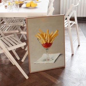 Pode incluir: Uma pintura emoldurada retrata um copo de martini cheio de batatas fritas e ketchup. As batatas fritas s&atilde;o amarelo dourado e o ketchup &eacute; vermelho vibrante. A pintura est&aacute; sobre um fundo neutro e sobre uma guardanapo branco.