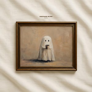 May include: A framed print depicting a ghost figure holding a small brown cup. The ghost is draped in a white sheet, with two black dots for eyes. The artwork has a vintage aesthetic, with the text "VINTAGE GLOW PRINTS" at the top.