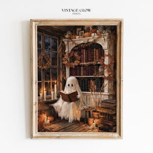May include: A framed art print titled VINTAGE GLOW PRINTS featuring a ghost wearing round glasses and reading a book. The scene includes a white bookshelf filled with books, autumn leaves, pumpkins, and lit candles near a window in a room.