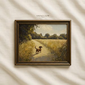 Pode incluir: Pintura de paisagem emoldurada com um cão dachshund castanho a caminhar num caminho de terra através de um campo de erva dourada. A obra de arte tem uma estética vintage, com uma moldura castanha escura e o texto "VINTAGE GLOW PRINTS" no topo.