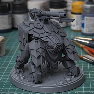 May include: A grey miniature model of a robotic creature, featuring a cannon and blade. The model has a textured, armoured appearance and is positioned on a circular base. The design suggests a science fiction or fantasy theme.