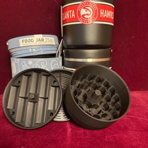 May include: A set of three ceramic mugs with a speckled, matte finish. The mugs are in shades of cream, light gray, and dark gray. Each mug has a simple, minimalist design and a rounded handle. The mugs are stacked on top of each other.