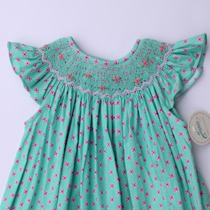 Hand‑embroidered dress for little girls.green smocked dress with ruffled sleeves and embroidered flower details.