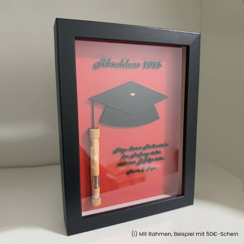 K&ouml;nnte beinhalten: Ein schwarzer Schattenfugenrahmen mit rotem Hintergrund, einer schwarzen Doktorhut-Silhouette, dem Text "Abschluss 2025", einem gerollten Geldschein in einem kleinen zylindrischen Sternenhalter sowie deutschem Text im unteren Bereich.