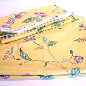 May include: Yellow fabric with a floral pattern featuring pink, blue, and green flowers. The fabric is folded and has a white label with the text "DuPont TEFLON" on it.