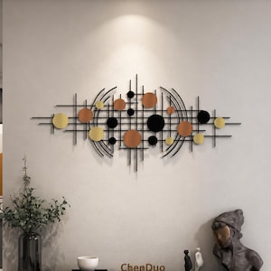 Può includere: Una scultura da parete orizzontale in metallo caratterizzata da una griglia di sottili linee nere intersecate da archi neri curvi. Il design è arricchito da vari dischi circolari in nero pieno, oro metallizzato e tonalità rame, creando una composizione.